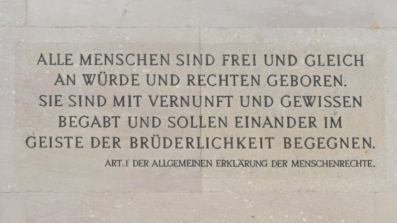 Inschrift, Artikel 1. der allgemeinen Erklärung der Menschenrechte: Alle Menschen sind frei und gleich an Würde und Rechten geboren. Sie sind mit Vernunft und Gewissen begabt und sollen einander im Geiste der Brüderlichkeit begegnen.