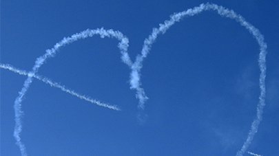 Blauer Himmel mit einem weißen Herz aus Flugstreifen 